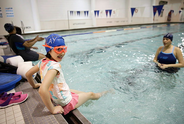 Девочка с аутизмом готовится прыгнуть в бассейн во время урока плавания в реабилитационном центре Нью-Йорка
