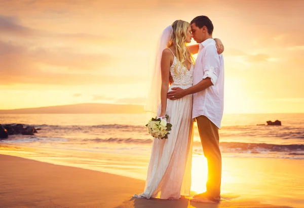 Жених и невеста, поцелуи на закате солнца на красивом тропическом пляже — стоковое фото