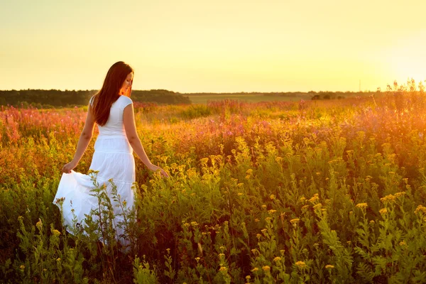 Молодая женщина в белой одежде, стоя в поле на закате — стоковое фото