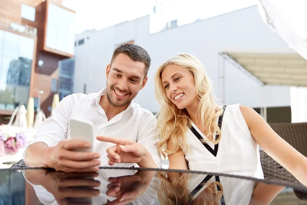 Счастливая пара с smatphone на террасе ресторана — стоковое фото