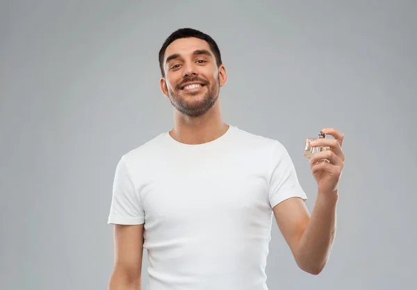 Улыбающийся человек с мужского парфюма над серый фон — стоковое фото