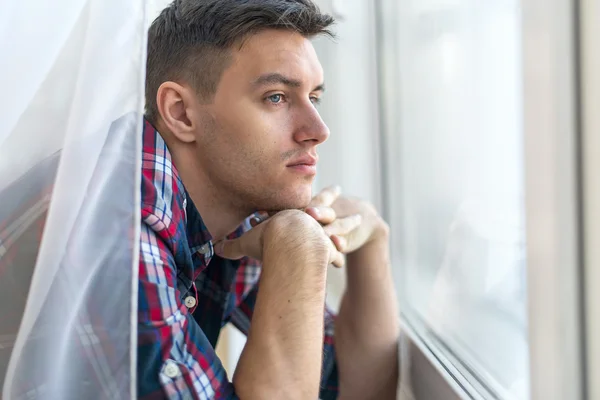 Задумчивый красавец парень смотреть через окна концепция грусть печаль боль ожидания — стоковое фото