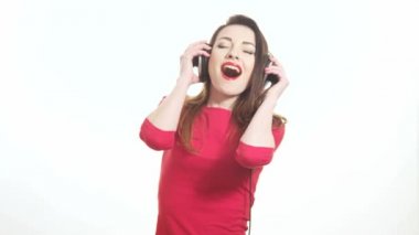 Сексуальная девушка в красном, положить на большие наушники и начинает качается на музыку и танцы и целуя изолированные на белом фоне средних выстрел — стоковое видео