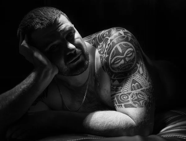 Жестокий человек мачо с татуировками на его руках. темный фон — стоковое фото