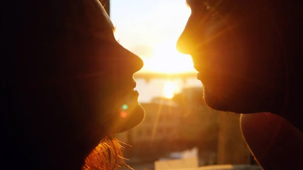 Романтический молодой пары в любви, глядя друг на друга на закат с солнце ярко за ними на горизонте — стоковое фото