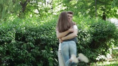 Парень обнимает и крутит в ее руки девушка в парке — стоковое видео
