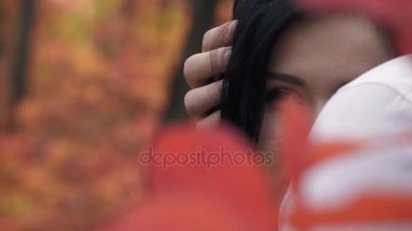 Среди красные осенние листья темноволосая женщина в руках человека и смотрит вдаль, медленное движение — стоковое видео