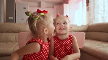 Две милые Твин сестры одеты в красный горошек платья. Играя вместе поцеловать друг друга улыбается — стоковое видео