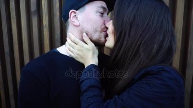 Портрет довольно любящей пары, прижавшись друг к другу и целоваться перед камерой на фоне деревянной стены на открытом воздухе в дневное время — стоковое видео