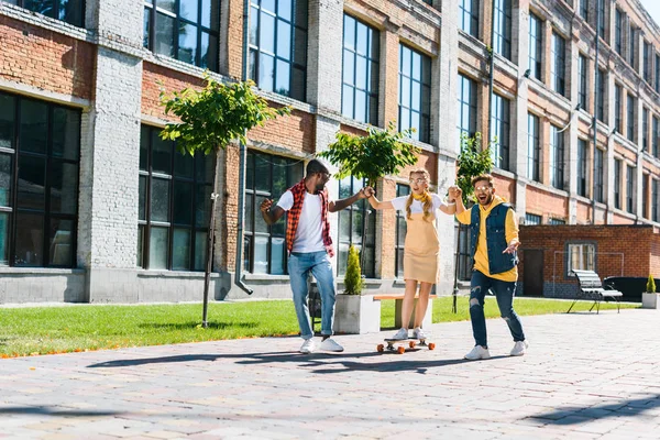 Многонациональное Мужчин Помогая Молодая Женщина Катание Коньках Longboard Улице — стоковое фото