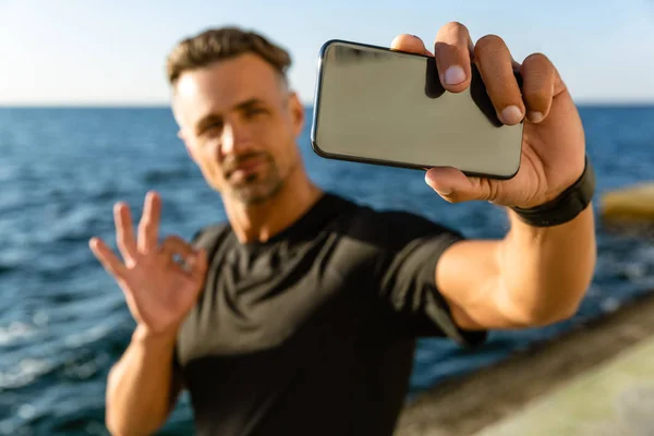 Handsome Adult Man Taking Selfie Smartphone Showing Okay Gesture Seashore — стоковое фото