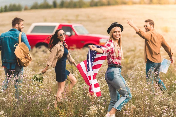 Group Happy Young American Car Travellers Flag Walking Flower Field — стоковое фото