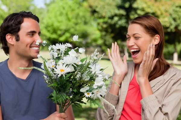 Женщина смеется взволнованно, как она представлена с цветами ее — стоковое фото