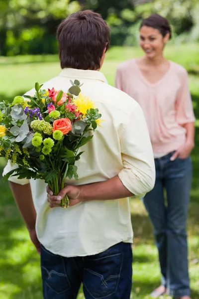 Человек собирается удивить его друг с букетом цветов — стоковое фото